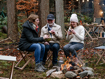 3 Menschen am Lagerfeuer im Wald