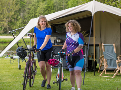 2 Frauen mit Fahrrädern vor Zeltanhänger